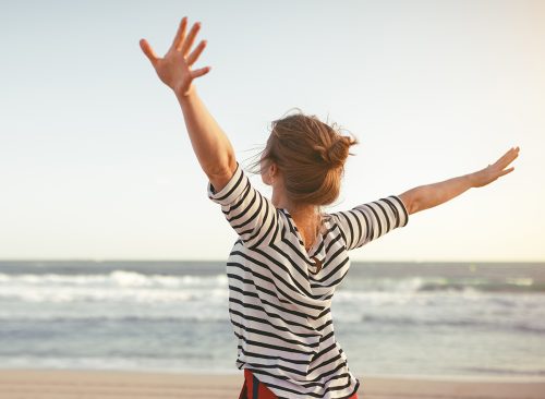 happy young woman enjoying freedom with open hands on sea