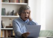 Shocked stressed middle aged mature 50s woman looking at paper document, feeling frustrated reading bad news, confused getting unpleasant information, having financial or professional problems.