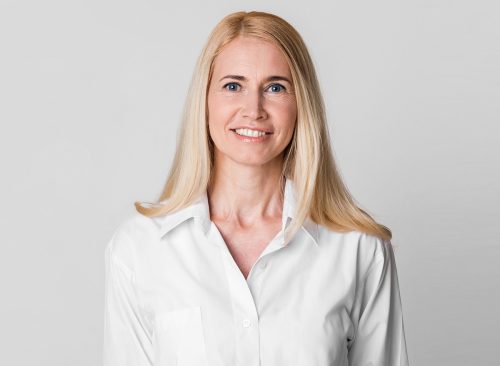 Natural Beauty. Smiling middle-aged female manager in white shirt posing to camera isolated over grey studio wall