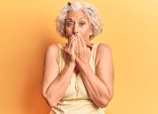 Senior grey-haired woman wearing casual clothes laughing and embarrassed giggle covering mouth with hands, gossip and scandal concept