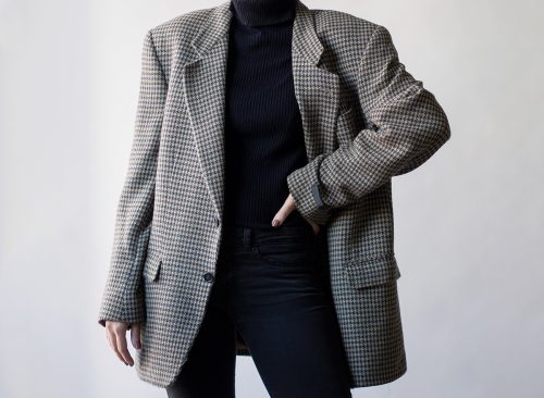Woman wearing stylish outfit with black turtleneck, oversized check blazer and black jeans isolated on white background. Copy space