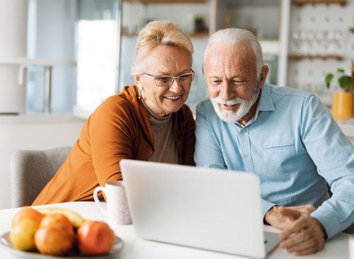 Happy mature couple using laptop at home