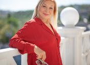 Beautiful blond middle-aged woman dressed red shirt walking in the street. Outdoor portrait of a 55 - 60 s ears old woman. Close up of fashion urban outfit