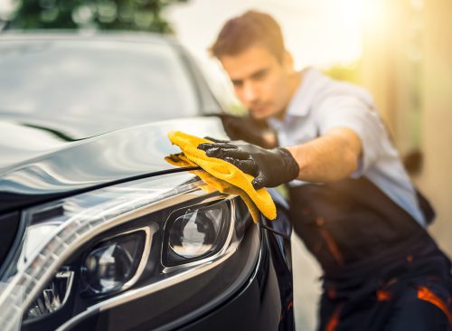 Car detailing - the man holds the microfiber in hand and polishes the car. Selective focus.